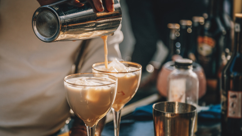 bartender pouring cream drinks into two glasses