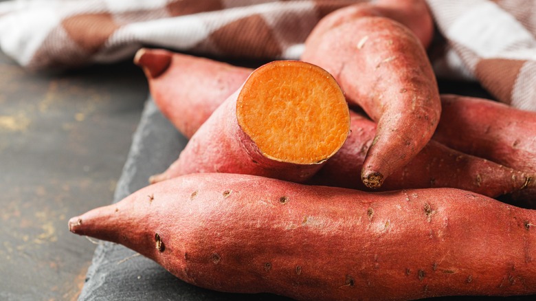 Fresh sweet potatoes on a dark, rustic background.