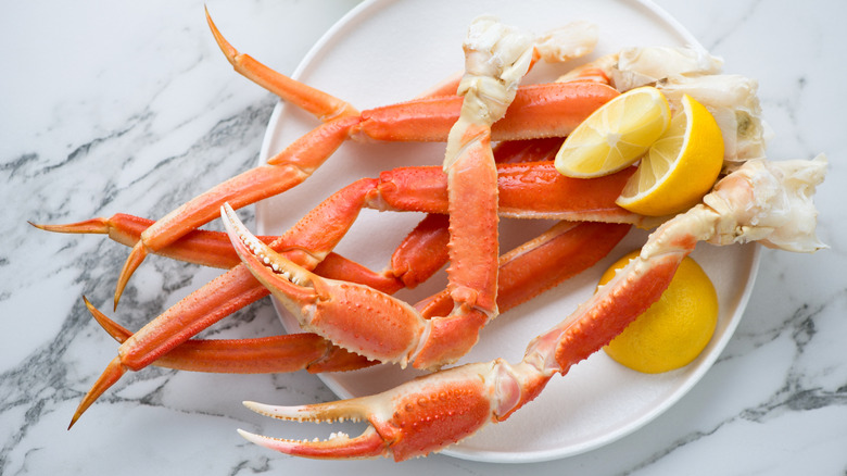 White plate full of red crab legs and lemon slices