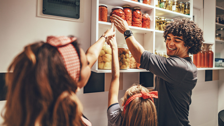 A family with two kids pulls organized jars from the pantry